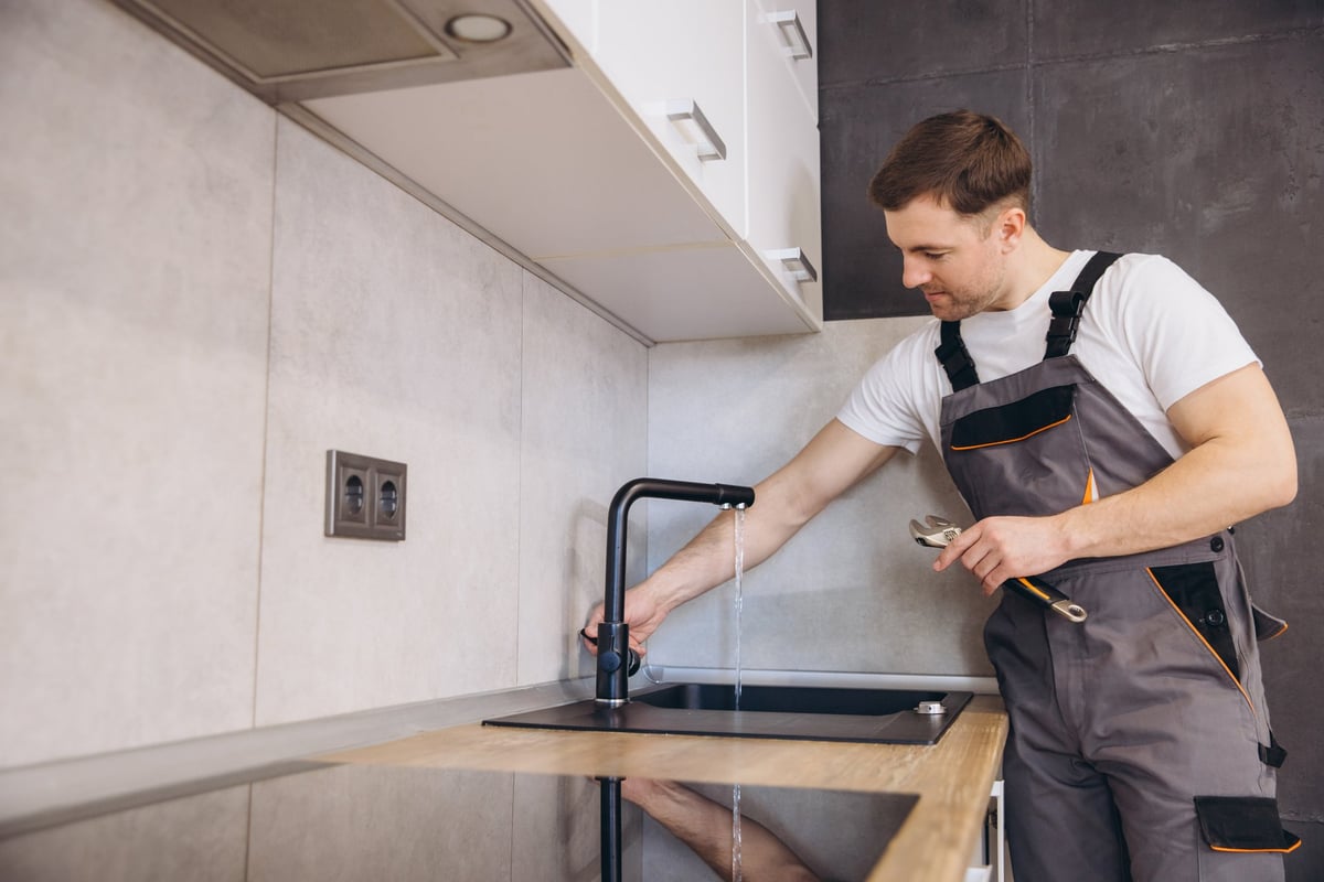 Professional Mississauga plumber working on kitchen faucet