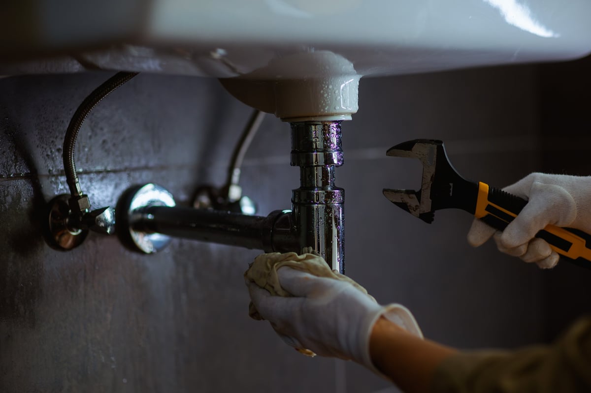 Emergency plumber repairing pipes under a sink in Mississauga Ontario