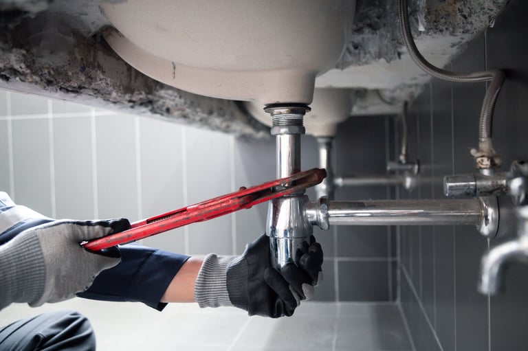 Plumber fixing a water pipe under a bathroom sink